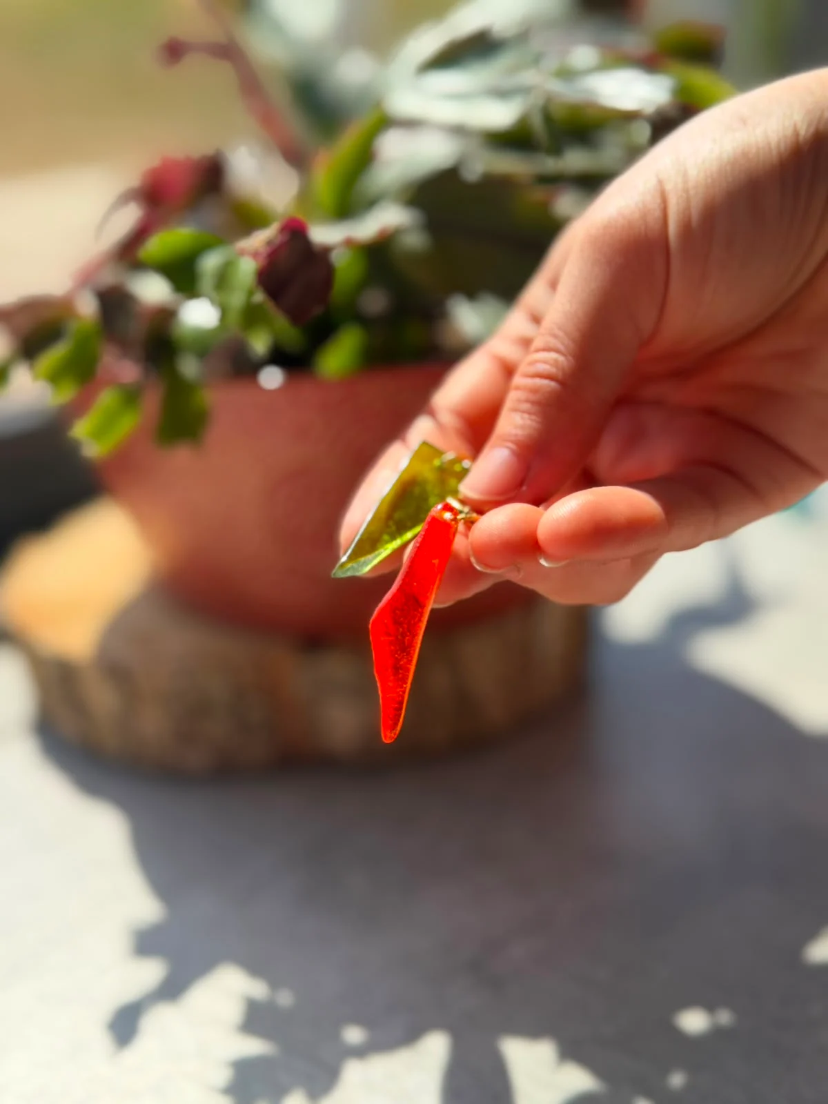 Pendentifs en verre translucide vert et orange tenus à la main à la lumière naturelle