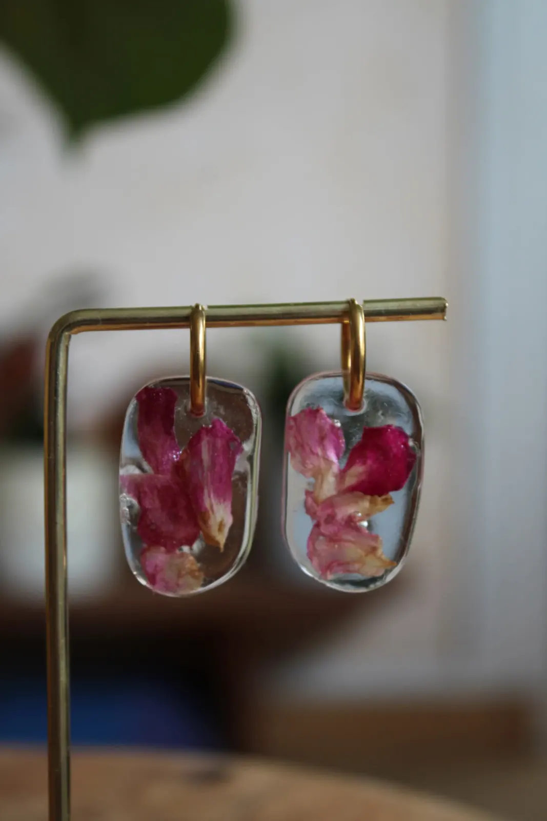Paire de boucles d'oreilles pendantes en résine aux pétales roses suspendues sur un support doré