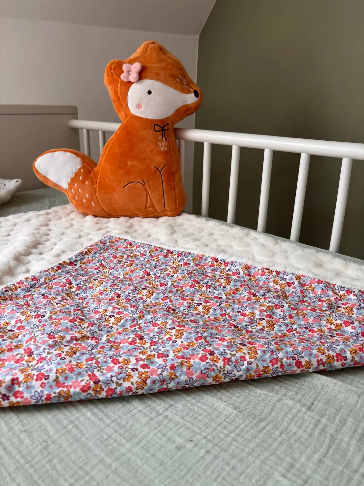 Couverture pour bébé à motif fleuri posée sur un panier en osier en extérieur