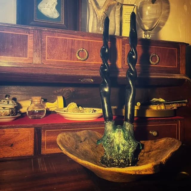 Vue d'ensemble du bougeoir artisanal avec ses longues bougies torsadées noires, posé sur un secrétaire en bois.