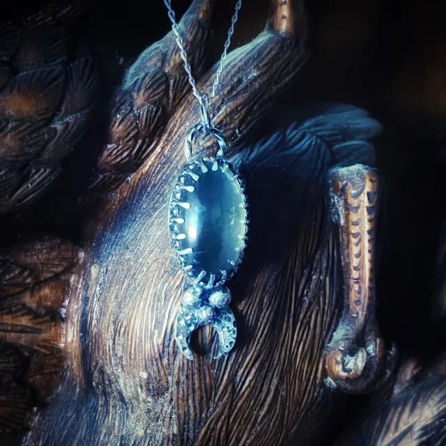 Vue rapprochée en biais du collier Selene avec cabochon ovale et croissant texturé.