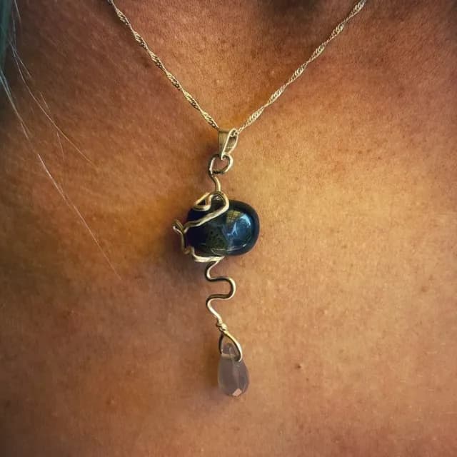 Gros plan du pendentif en argent porté au cou, orné d'une agate mousse et d'une goutte d'agate grise