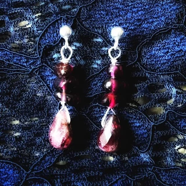 Paire de puces d'oreilles en argent avec perles et gouttes de pierres bordeaux sur dentelle bleue.
