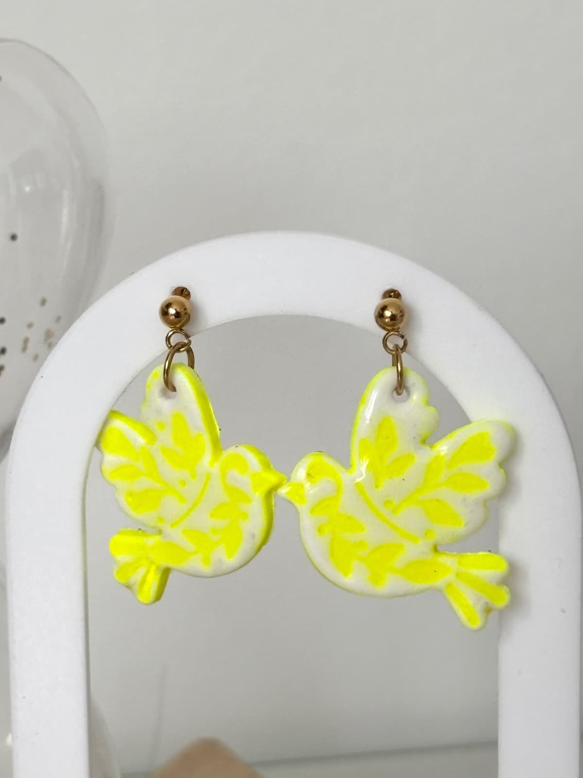 Vue d'ensemble de la paire de boucles d'oreilles légères motif oiseau blanc et jaune éclatant