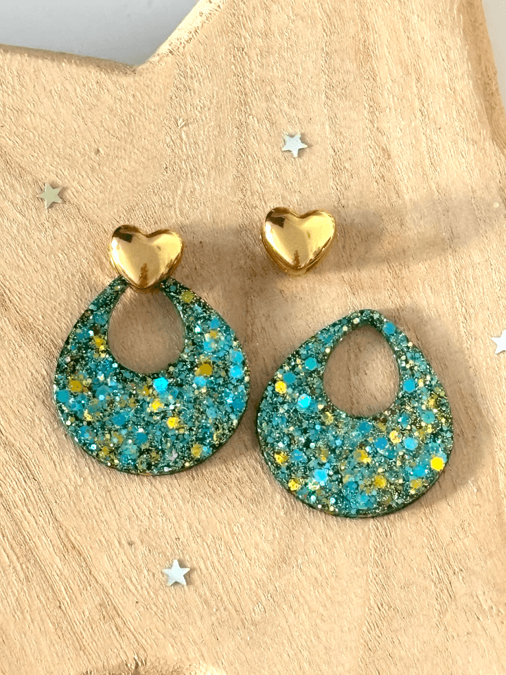 Clous cœurs dorés séparés des pendentifs ajourés aux paillettes turquoise sur fond blanc