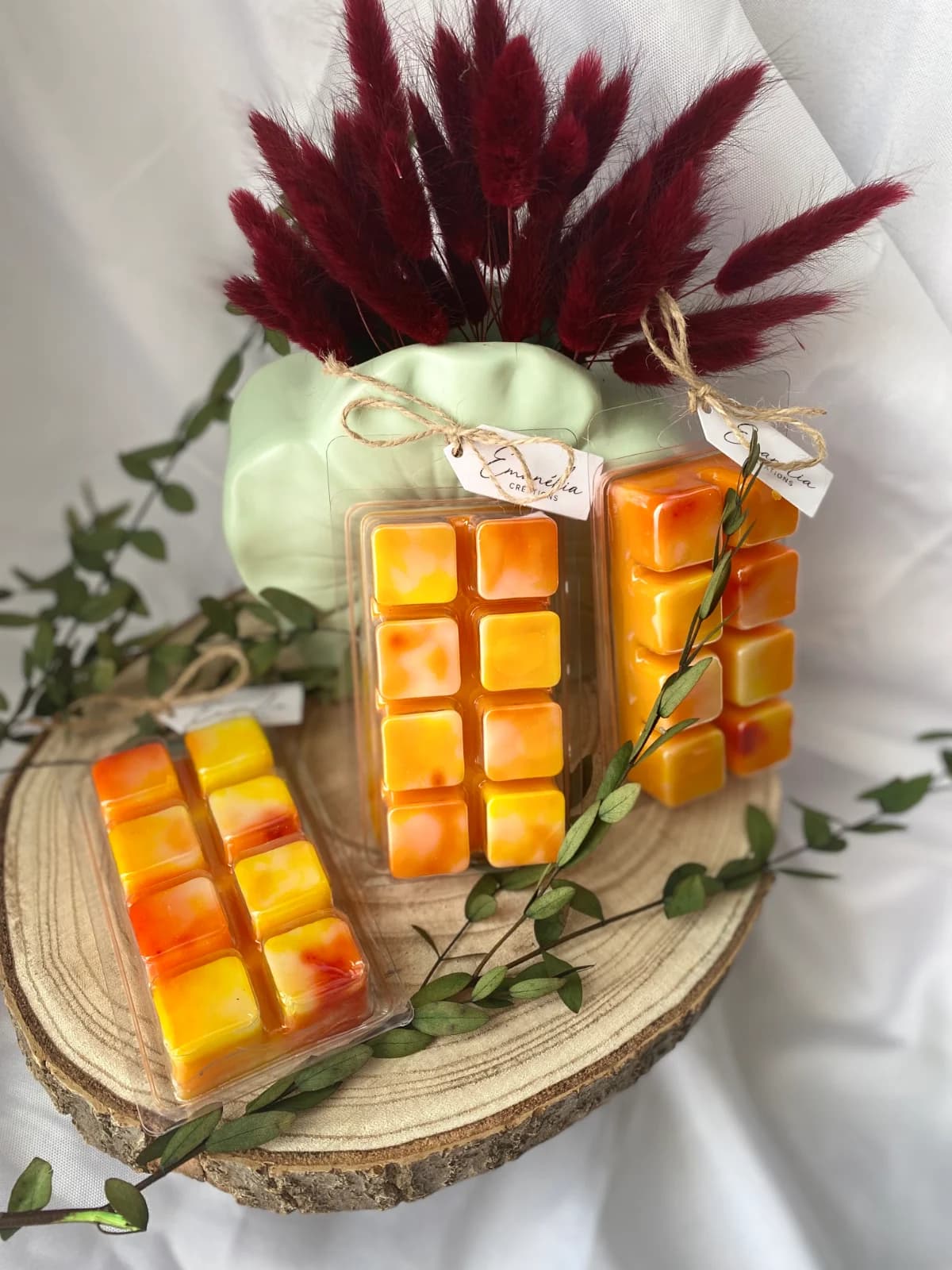 Tablettes de cire à fondre marbrées orange et jaune dans leurs étuis transparents ornés d'une ficelle.