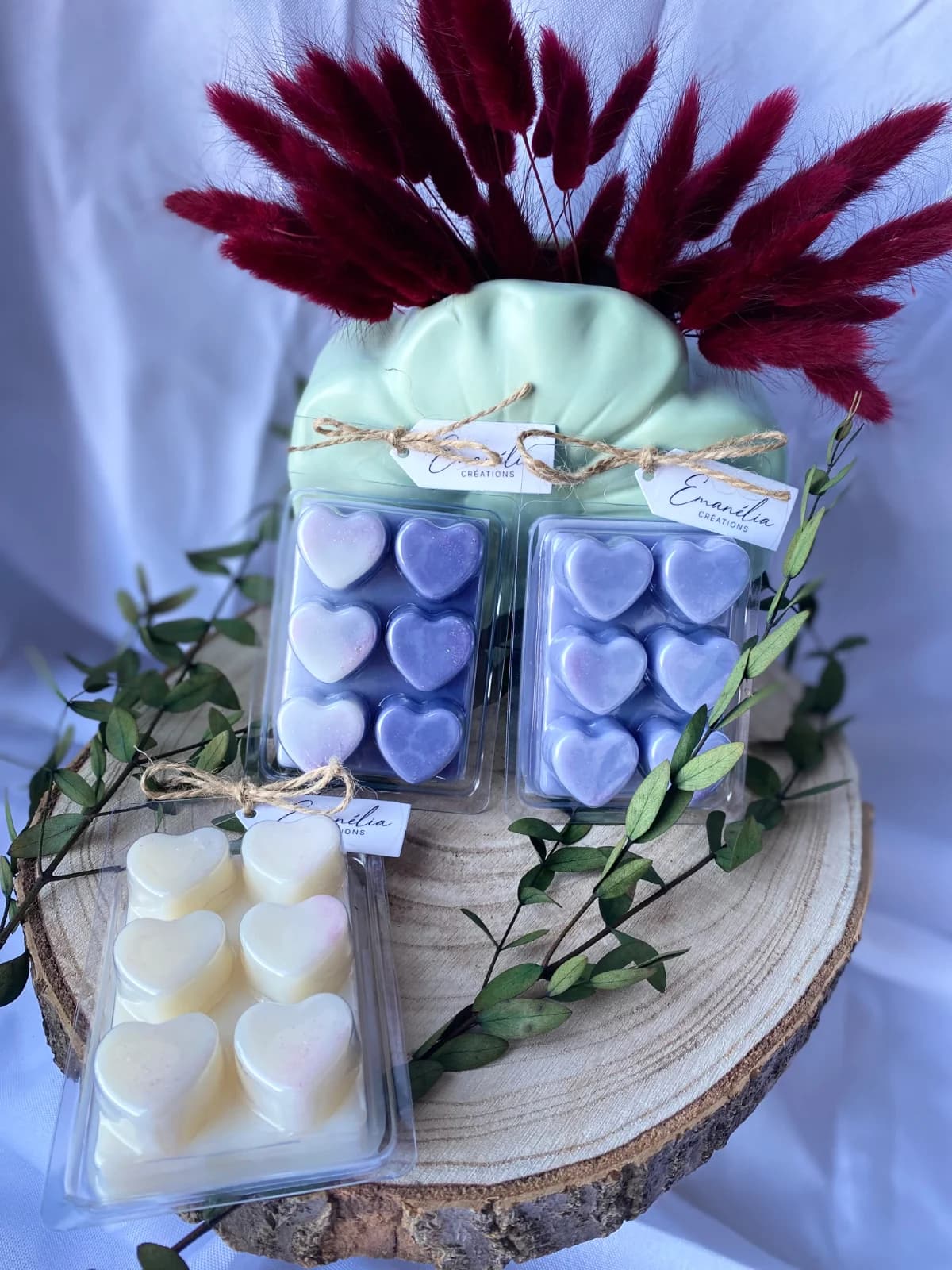 Tablettes de cire parfumée en forme de cœurs violets et blancs présentées sur un rondin de bois.