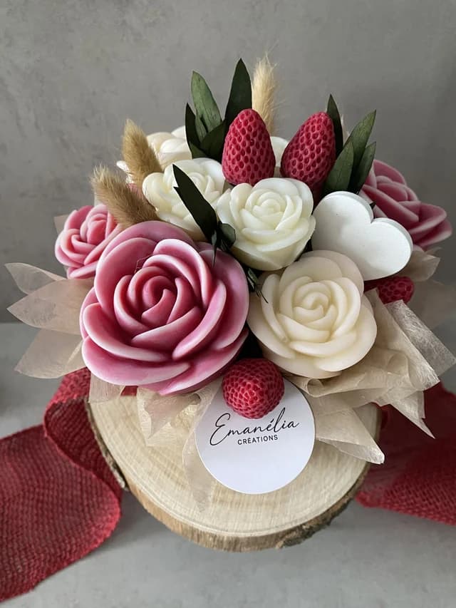 Vue du dessus du bouquet de fleurs sculptées roses et blanches parsemé de petites fraises rouges et d'un cœur.