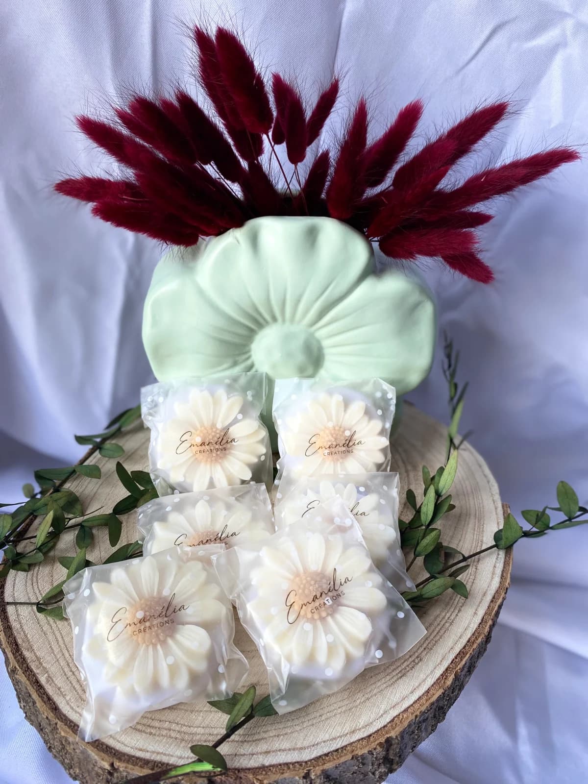 Fondants parfumés en forme de marguerite sous sachet, disposés sur un rondin de bois décoré.